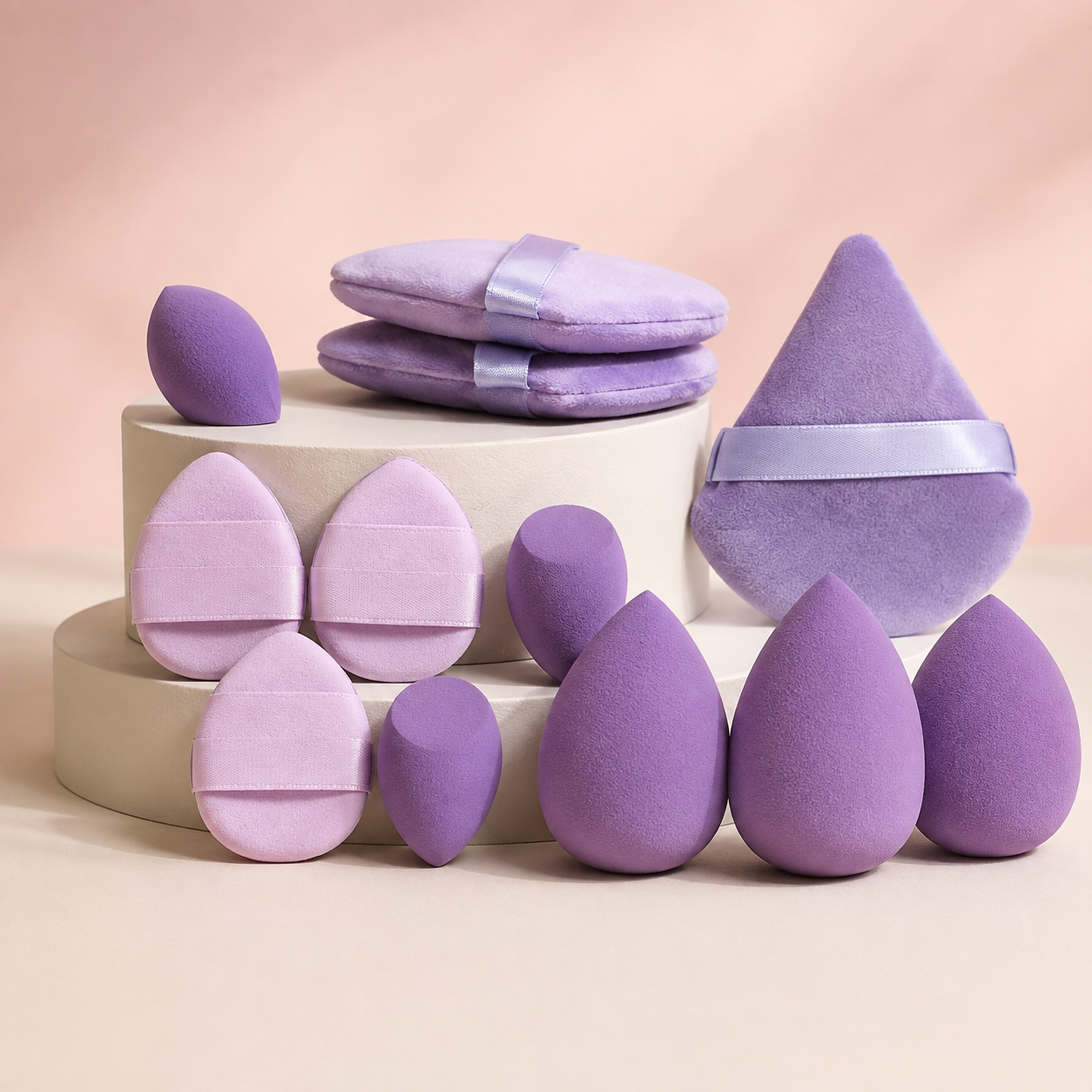 Lavender makeup sponge and powder puff assortment on cream display plinths